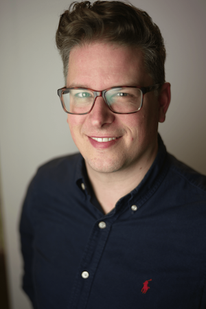 Portret of Jelle Kralt, smiling, posing for a gray background looking at the camera